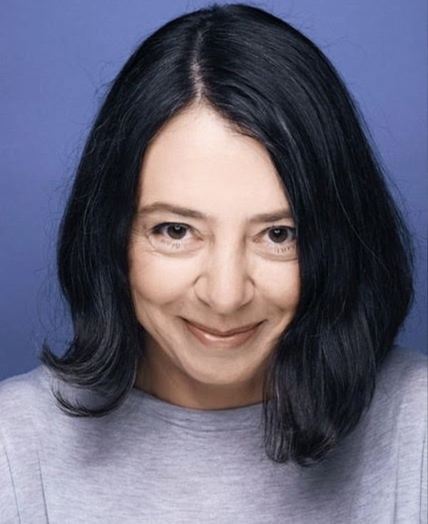 Portret kobiety en face. Brunetka, włosy do ramion, uśmiechnięta.