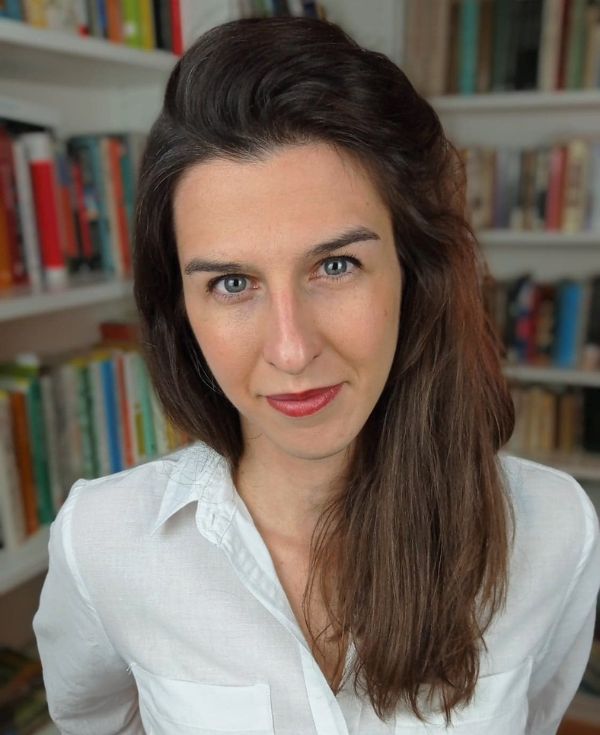 Portret kobiety o brązowych włosach, w białej koszuli.