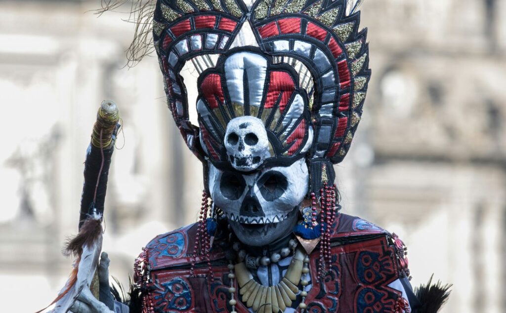 Zdjęcie przedstawia osobę w masce używanej przy obchodach dia de los muertos w Meksyku.