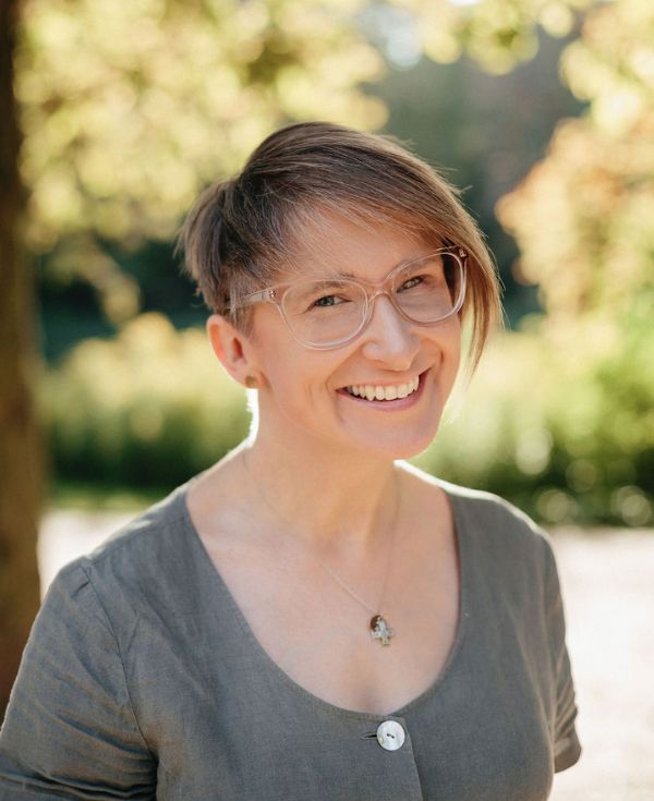 Uśmiechnięta kobieta o krótkich włosach, w okularach