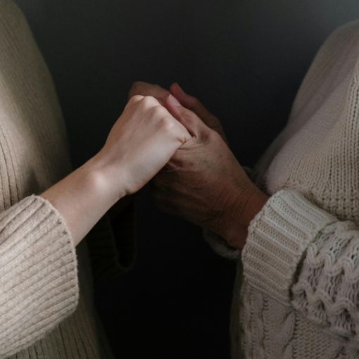 Osoby stojące na przeciwko siebie i trzymające się za ręce.