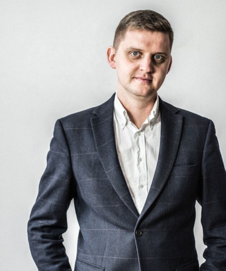 Mężczyzna w marynarce patrzący w aparat