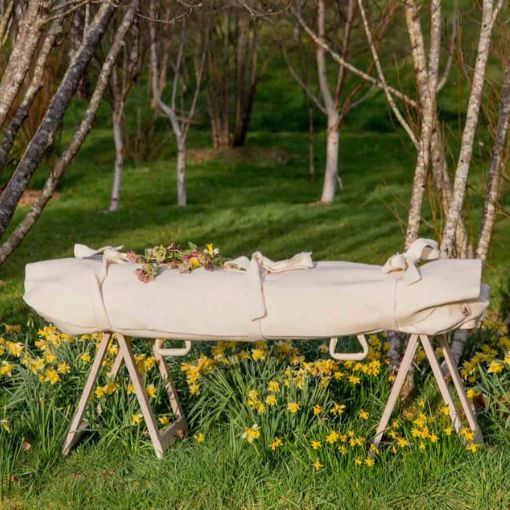 Biała trumna między drzewami.