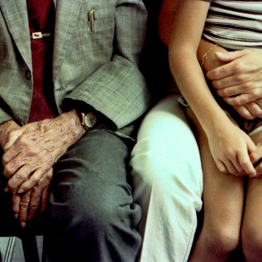 Starszy mężczyzna i siedząca obok niego kobieta z dzieckiem na kolanach.