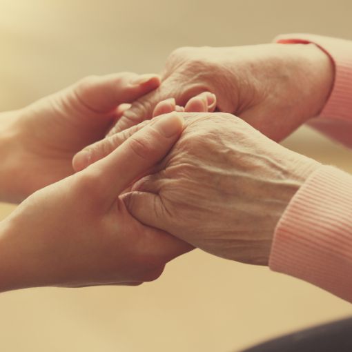 Dłonie trzymające ręce starszej osoby.