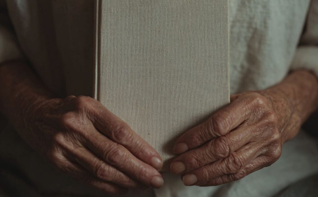 dłonie starszej osoby trzymające książkę